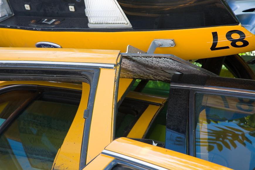 Jumbled up taxicab doors and trunk deck Cambridge Massachusetts doors and decklids painted in yellow and black, removed from vehicles and piled up haphazardly, the windows still in the doors, taillights and the number 87 can...