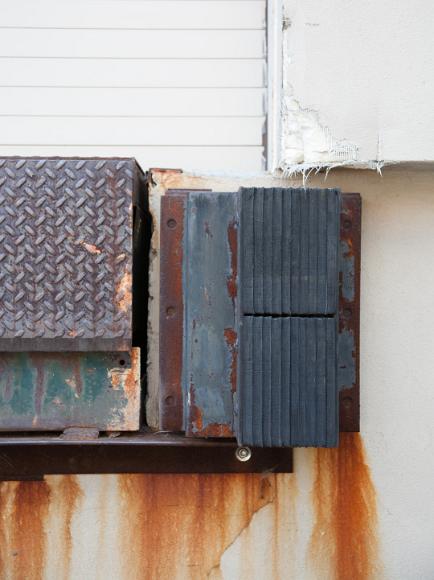 Loading dock detail Cambridge Massachusetts Closeup, taken from knee level of the end of a loading dock, showing rubber bumbers and a rusted metal diamond plate cover, all dripping streaks of rust onto...