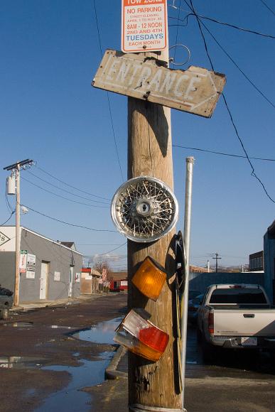 Pole with turn signals wire wheel and signs behind Union Square Somerville MA Signs stuck on a pole in front of a puddled road