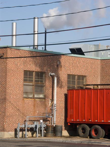 Loading dock with active smokestacks in a uniform cleaning business behind Union Square Somerville MA Brick building belching smoke with red painted truck pulled up to it