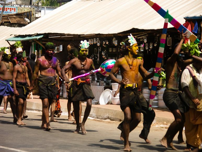 Dancing men on the Sabarimala pilgramage Men, barefoot and stripped to the waist wearing only necklaces and black sarongs, covered in mutlicolored paint many with masks and large swords or props dance...