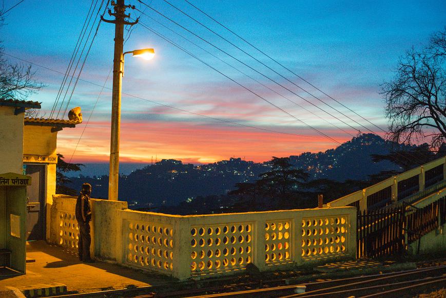 A man and a monkey look at the sunset over Summer Hill in Shimla, Himachal Pradesh