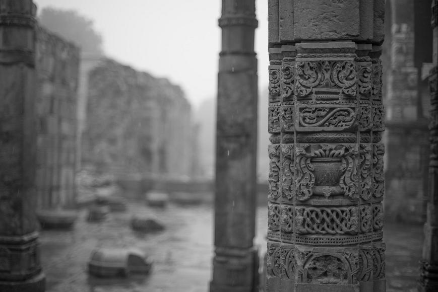 Reused column A ornately carved stone column from an ancient hindu temple is reused in Muslim Tomb in India in the rain