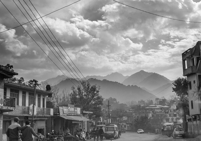 Village scene A road along a small village near Dharamasala India with steep forested mountains as the backdrop, criss-crossed with power lines and with dramatic clouds in...