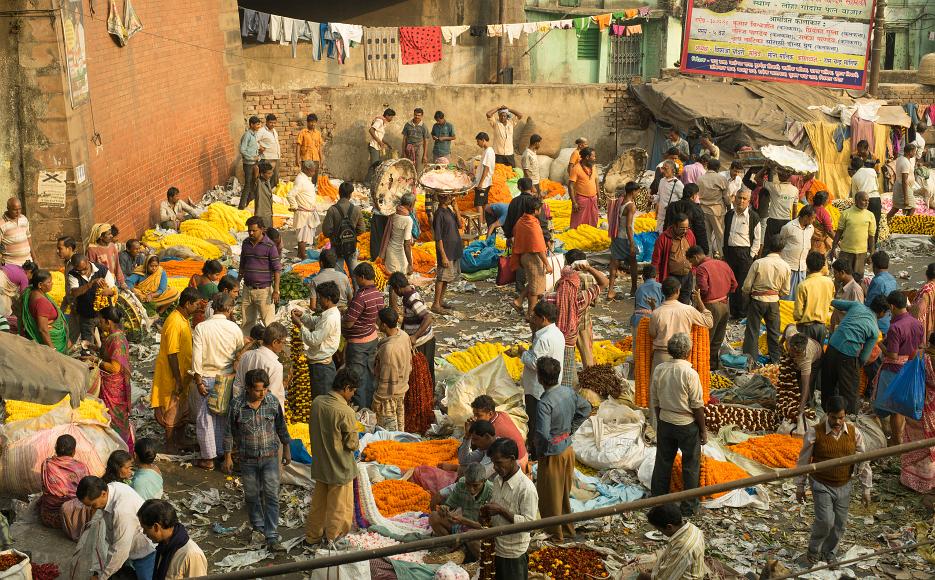 Howrah flower market Men and women throng around garlands of brightly colored flowers, mostly yellow and organge in Kolkata, India