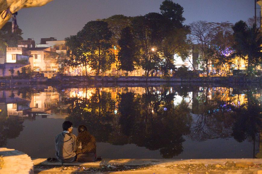 _DSC1107 A couple sits in fron of a water tank that reflects trees and lights at Layalka Mat, Kolkata, India