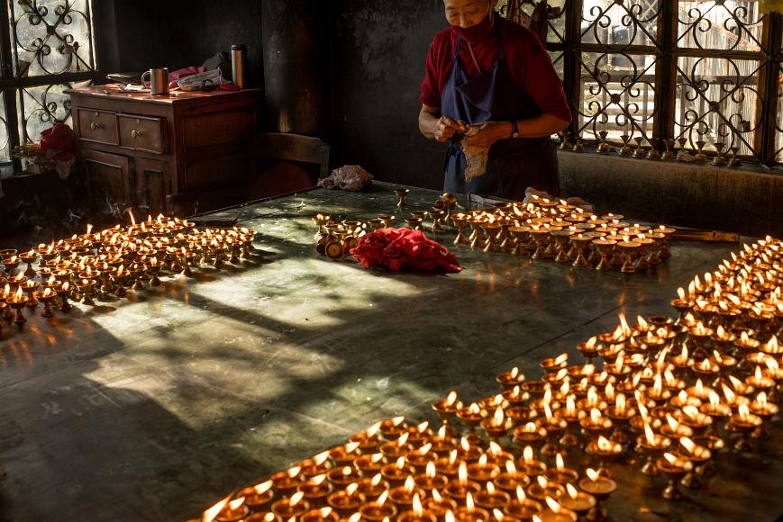 Buddhist Monk lighting candles At the Dalai Lama's temple at the Tibetan government in exile in Dharamasala