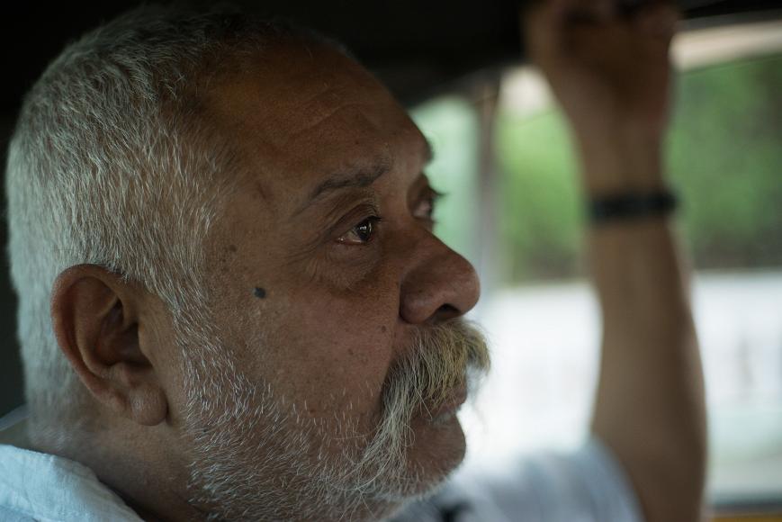 My uncle in a cab Old man with a long mustache and short silver hair and beard sits with arm up in a cab