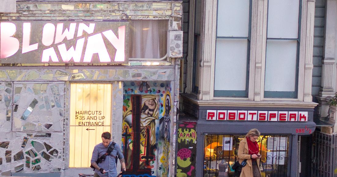 Dont even see each other Two people standing on Haight St in the Lower Haight both look down at iPhones in front of blown away salon and robotspeak electronica store