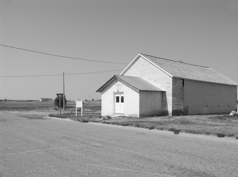 AME Church in Nicodemus Kansas Black and white photograph by Rana Banerjee of a white church in a state of disrepair with AME and written across it, built in 1885, now standing at the edge of...