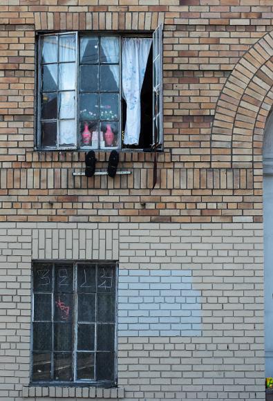 Shoes hang outside a window in Chinatown A pair of shoes hangs on a hanger outside of a window in Chinatown with another closed window below