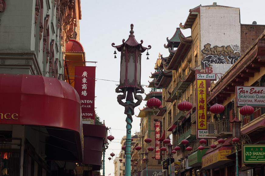 Chinatown street scene with lanterns and ornate lamps Buildings on the street in Chinatown in San Francisco in the late afternoon with Chinese architectural elements on many of the buildings signs for Chinese...