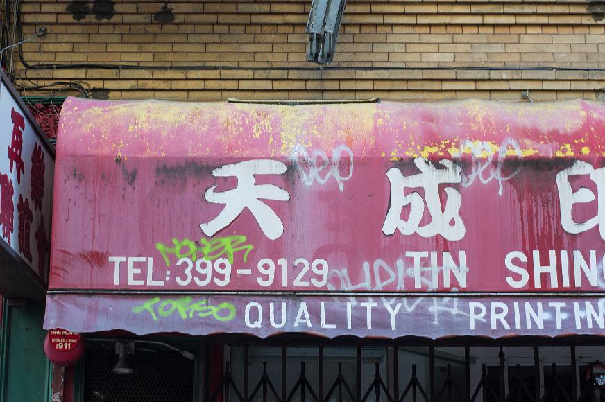 Chinatown wall detail #5 Closeup view a a battered fading spray painted and mildewed sign for a printing shop in Chinatown