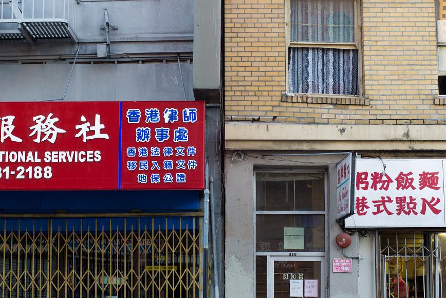 Chinatown wall detail #4 Two closed businesses with metal grates pulled across their shopfronts with signs lettered in mostly Chinese and some English