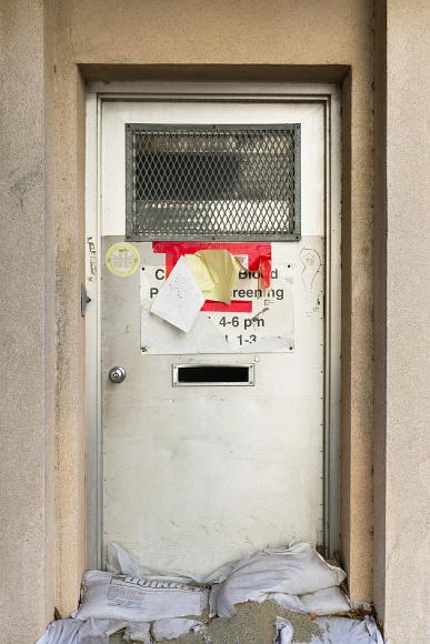 Sanbags in doorway Sandbags and sand block the bottom of a silver metal door that has a partially covered sign in front of it