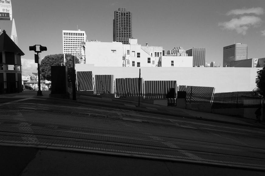 Angled Street Cable Car tracks in chinatown near downtown San Francisco California with a fence providing silhouetted structural elements against a backdrop of tall building...