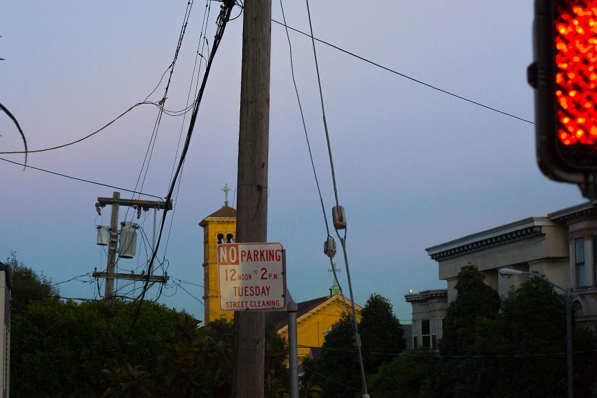 SF Scene at dusk in the city No parking sign crosswalk sign and victorian buildings and power wires and power poles near the Lower Haigh and Alamo Square in San Francisco California