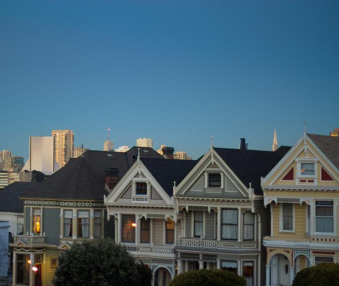Ladies of paint Painted ladies and a catholic church in white stone and the transamerica building peeking out beihind with many white buildings near Alamo Square in San...