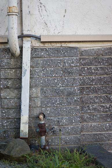 Wall detail Downspout emptying onto a rock with a spigot and some grass