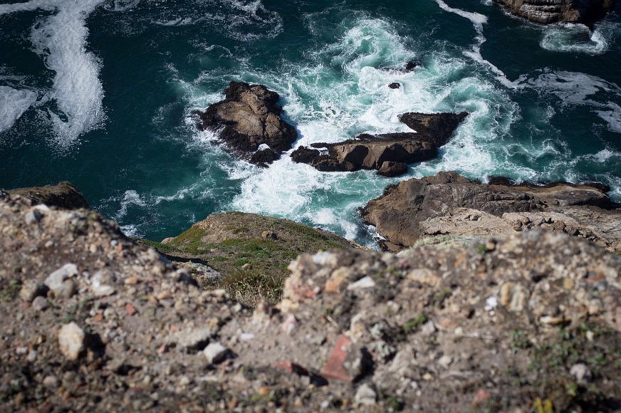 Looking down is not a good idea Looking down over a large cliff to the sea waves crashing on the inhospitable rocks below