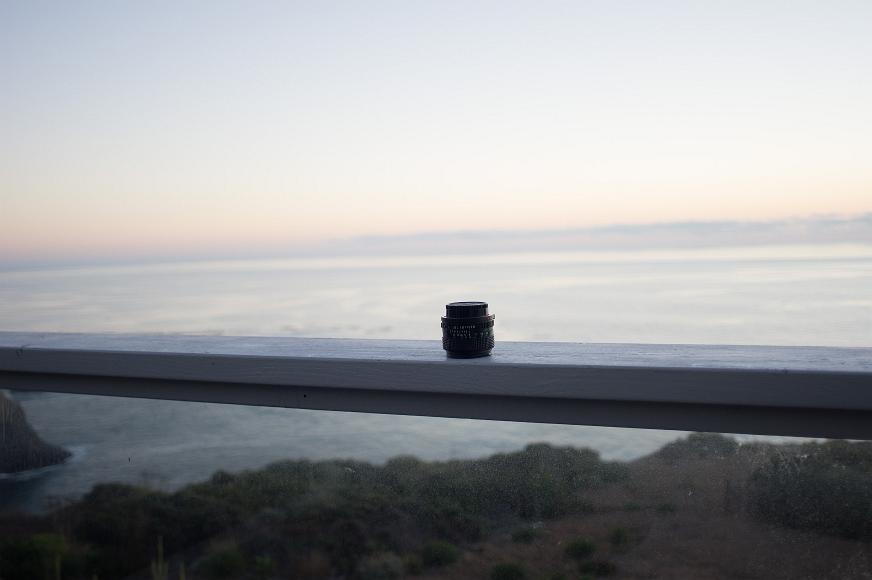 One lens, one oceans Canon fd 50mm f1.4 lens sits atop a railing at a beachhouse on the Pacific Coast in North