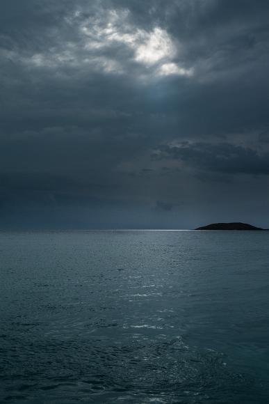 Culebra Island and the turquoise ocean Sunbeam burts from the sky glistening on the ocean with a dark island visible in the background
