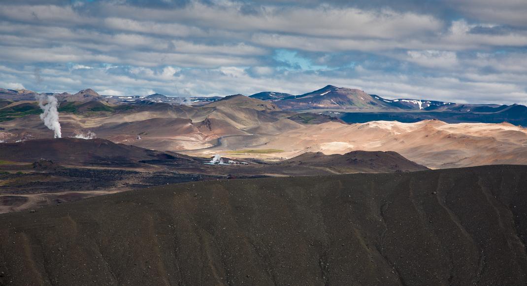 Steam from hydrothermal plant in northern Iceland over volcanic hills Where the earth is splitting apart literally