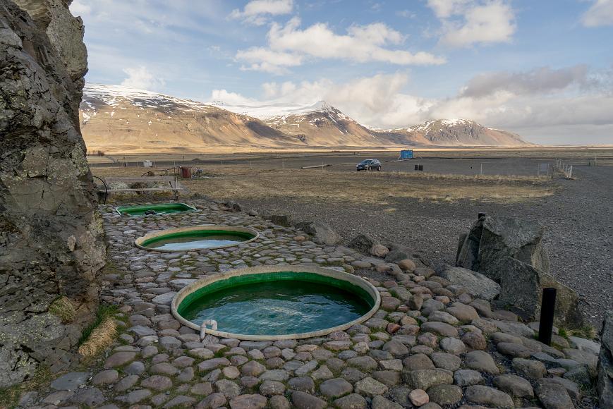Three pools, our conveyance, and some mountains Three Hot Tub pools with another two not visible in a broad valley near Hofn, empty but for us, perfectly temperate in turn, and beneath the crazy skies and...