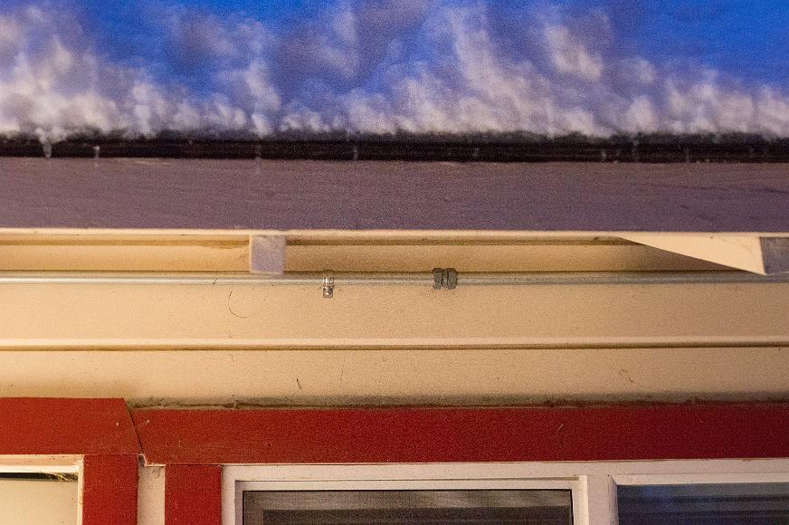 Three layers of roof with red white and blue Blueish snow on a roof with white paint and a red window edging at a cabin in South Lake Tahoe California