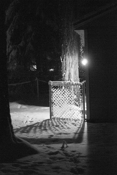 Snow fence shadow Outdoor light shines through a fence that has snow on it casting a shadow into the snow with snow falling in South Lake Tahoe California