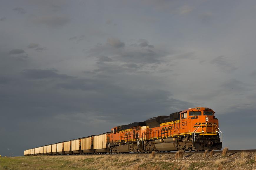 Burlington Northern Santa Fe locomotive pulling coal cars across Nebraska's Platte River Valley just before sunset train with cars across the plains