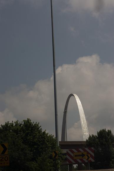 St Louis Arch St Louis' Gateway arch sparkles in the sunlight against a partl cloudy sky above trees and highway signs