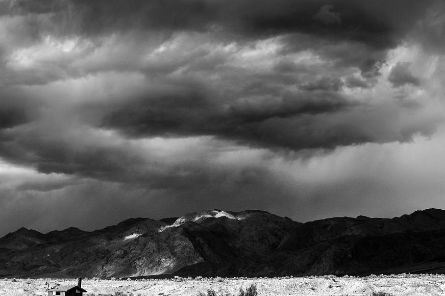 Light and storms on an outhouse and desert mountains in Death Valley NP At the Saling Valley Warm Springs near the National Park Service outhouse