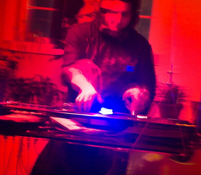 Jeff spins records in red light jeff spins records on a glass table suspended from the ceiling on new years eve of 2007. His hands are blurry from spinning and the entire scene is bathed in an...