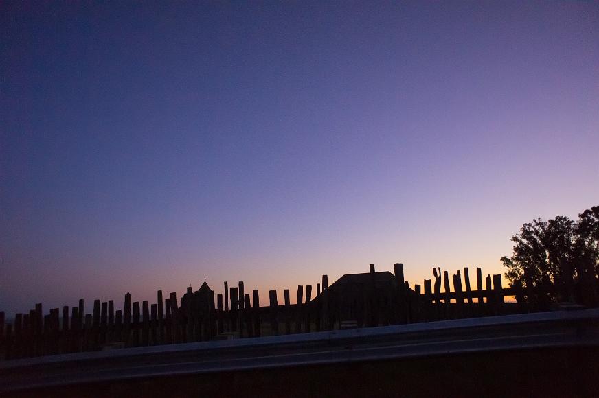 Crosses and railings by the ocean after sundown Metal railing wooden fence, church and other buildings and trees silhouetted against a post sunset sky along California Highway 1 along the coast north of San...