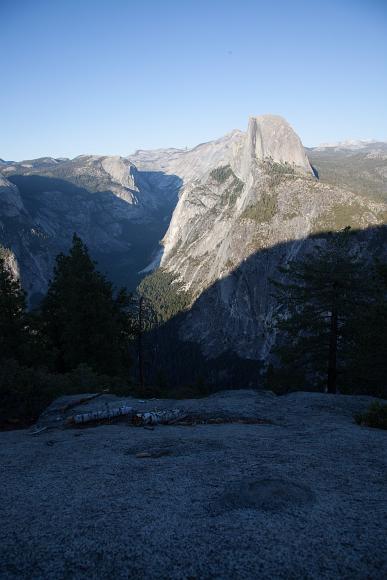 Half Dome almost in shadow from Glacier point Granite rocks n the foreground and in the peaks of the Yosemite high country and Half dome as seen from from Glacier Point