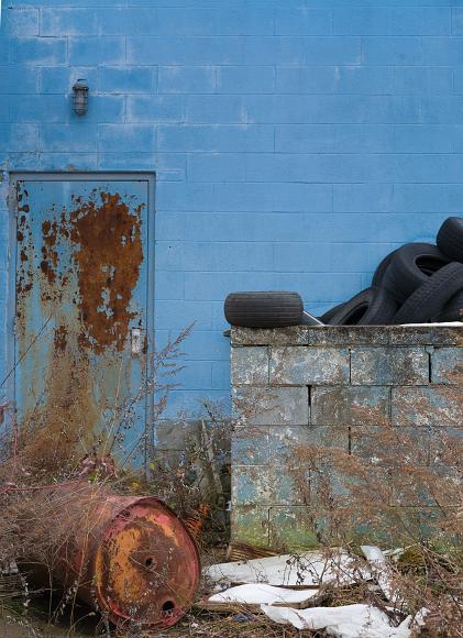 Old tires and barrels against a blue wall, Abandoned gas station detail #2