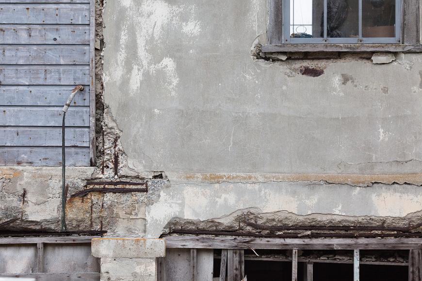Alcatraz detail #3 Abstract of a crumbling wall of a building on Alcatraz with an exposed rebar an exposed window frame and whole window with a fake owl in it