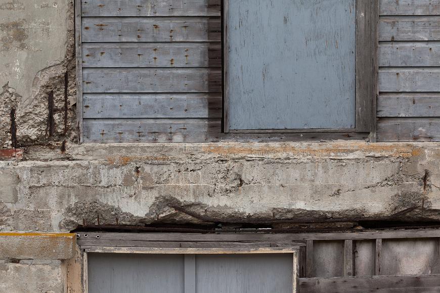 Alcatraz detail #4 Crumbling wall with painted grey wooden slats, exposed rebar and wooden door and window frames