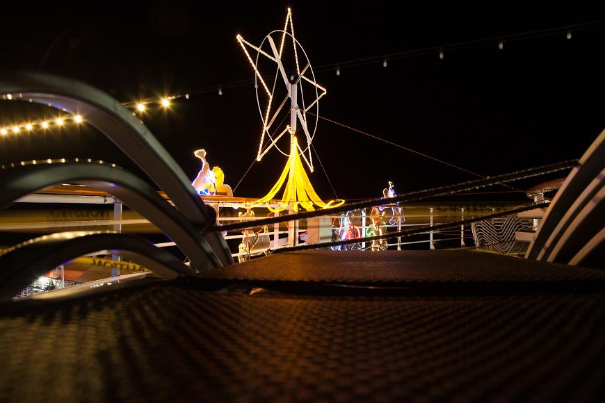 Christmas decorations at night on a Carnival Cruise ship A large lit up star, a Santa with reindeer lit up by multicolored lights and a string of lights as seen from a lounge chair at night on a Carnival Cruise ship