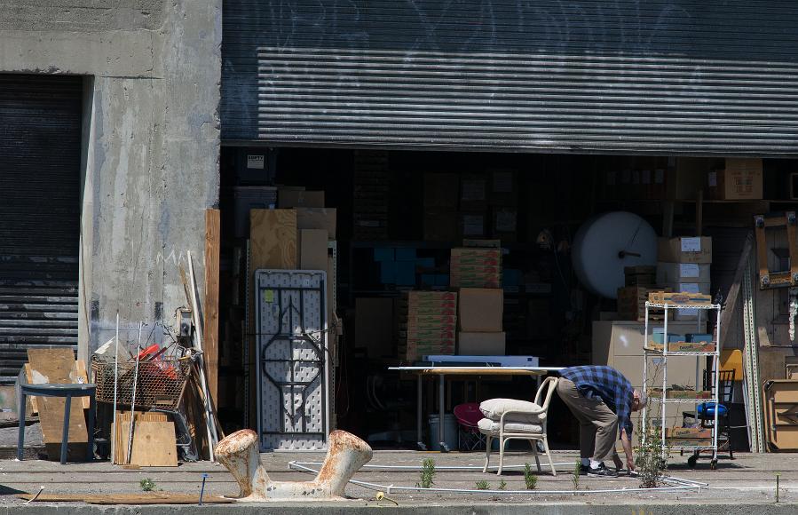 San Francisco Pier Detail #7 man bent over in front of pier storage unit with boxes shelves tables and other assorted items